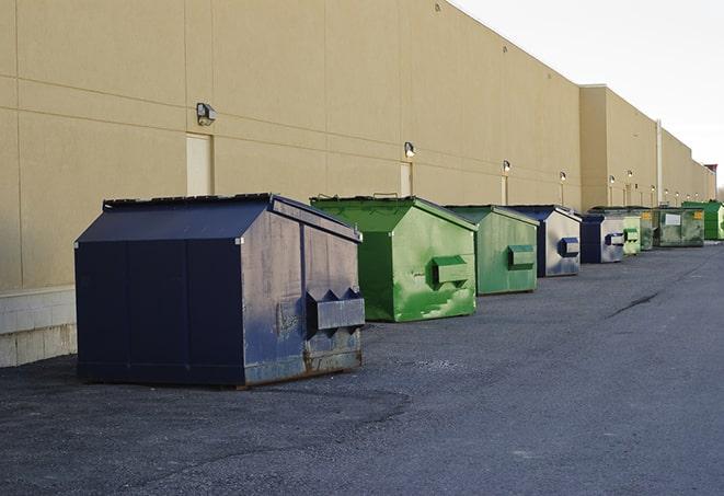 a construction worker empties a wheelbarrow of waste into the dumpster in Beaumont